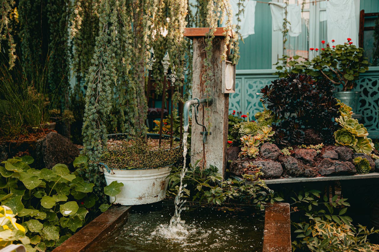 Lush garden setting with flowing water faucet and abundant greenery creating tranquility.